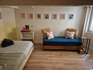 a room with two beds and a blue couch at 17m2 Flower studio dans le centre historique Ecusson in Montpellier