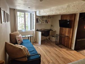 a living room with a couch and a desk at 17m2 Flower studio dans le centre historique Ecusson in Montpellier
