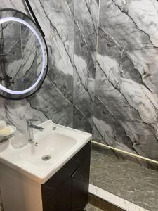 a bathroom with a sink and a marble wall at Tunduk Lux House in Teploklyuchinskoye
