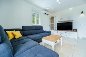 a living room with a blue couch and a tv at Holiday house Gloria in Vrbnik