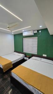 a room with two beds and a green wall at S J RESiDENCY in Trivandrum