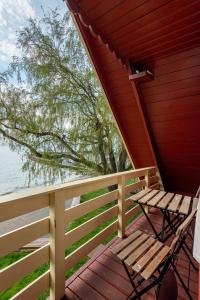 a wooden porch with a bench and a tree at Poilsio namai El Nido in Nida