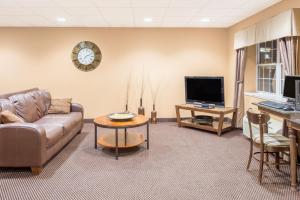 a living room with a couch and a tv and a table at Microtel Inn & Suites by Wyndham Quincy Downtown - River Area in Quincy
