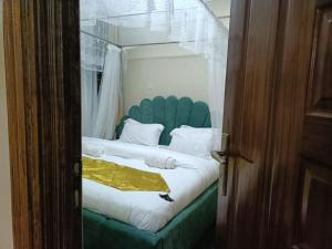 a bedroom with a bed with a green headboard at Riverview greenstar homes in Kisii