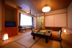 ein Wohnzimmer mit einem Tisch und einem TV in der Unterkunft Hotel Grand Mer Sankaiso in Ajigasawa