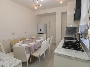 a dining room with a table with chairs and a kitchen at 5 Gelli Terrace in Caerphilly