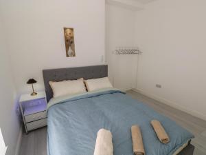 a bedroom with a bed with a blue blanket and two towels at 5 Gelli Terrace in Caerphilly