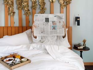 a person laying in bed reading a newspaper at Hotel Mercure Roma Corso Trieste in Rome +116 photos