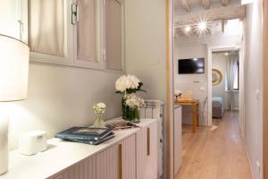 a kitchen and living room with white cabinets and flowers on a counter at La Piccola Atene Atelier in Pietrasanta