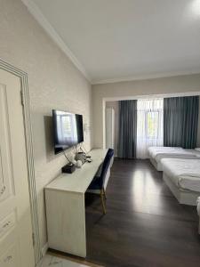 a hotel room with a bed and a desk with a television at Khan Plaza Hotel in Almaty