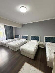 a room with three beds in a room at Khan Plaza Hotel in Almaty