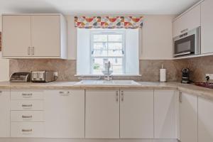 a white kitchen with a sink and a window at Brandoch Lodge in Logierait +23 photos