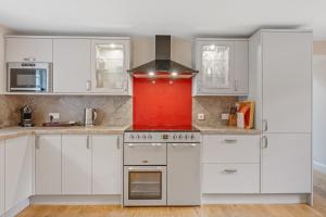 a kitchen with white cabinets and a red stove at Brandoch Lodge in Logierait