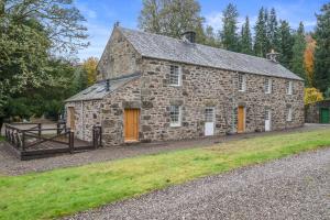an old stone building with orange doors and a fence at Brandoch Lodge in Logierait