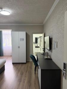 a room with a desk with a chair and a kitchen at Khan Plaza Hotel in Almaty