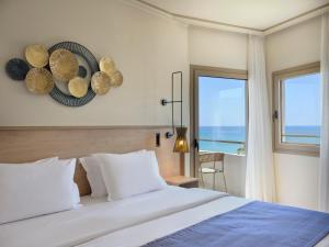 ein Schlafzimmer mit einem großen Bett und einem Fenster in der Unterkunft Atlantica Ocean Beach Resort in Maleme + 140 Fotos