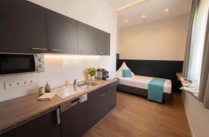a room with a bed and a kitchen with a sink at H24 Hotel Berlin Grünau in Berlin