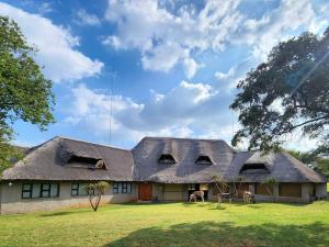 a house with a thatched roof on a field at Buyskop Lodge, Conference & Spa in Bela-Bela