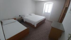 two beds in a small room with a window at Apartments Tomas in Ugljan