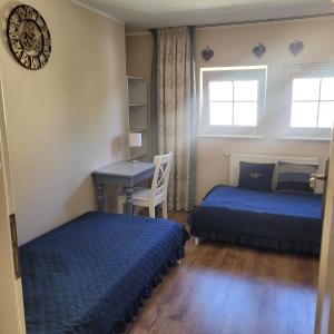 a bedroom with two beds and a desk and a clock at Słoneczne piętro w Kolbudach in Kolbudy