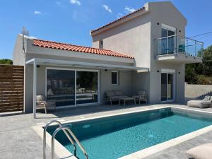 a villa with a swimming pool in front of a house at Zefy's Scenic Oasis in Pesádha