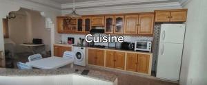 a kitchen with wooden cabinets and a white refrigerator at Dar Tantana sayafi in Hammam Sousse
