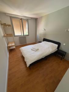 a bedroom with a bed with white sheets and a wooden floor at Hôtel café des cours in Cébazat