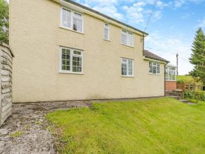 a large brick house with white windows and a yard at Mavis Cottage in Kington