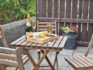 a wooden table with a bottle of wine and glasses at Combe Cairn in Millom