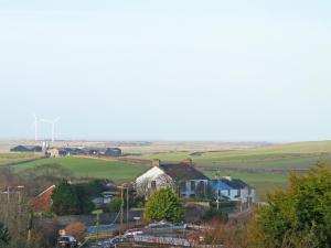 a small village with a wind turbine in the distance at Combe Cairn in Millom +8 photos