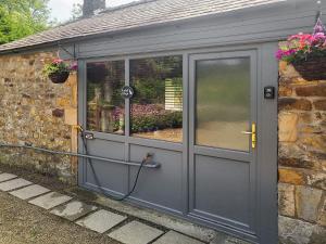 a greenhouse with a door with a hose at Acre Hill Cottage in Harrop Fold