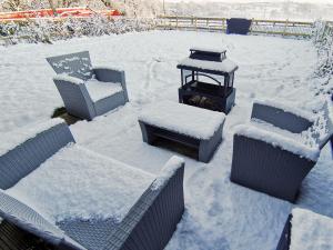 a yard covered in snow with chairs and a lantern at Acre Hill Cottage in Harrop Fold