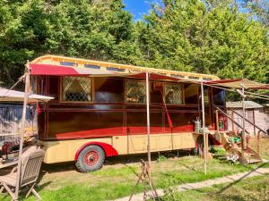 an old red and yellow bus parked in a yard at Romney Wagon in Hailsham