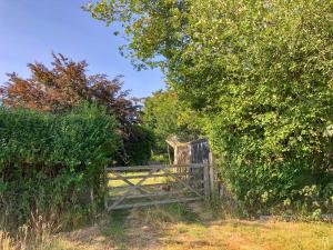 an old gate in a field next to some bushes at Romney Wagon in Hailsham