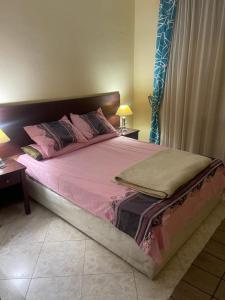 a bedroom with a large bed with pink sheets and pillows at El wadi Pearl Residence in Ain Sokhna +2 photos