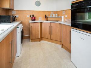 a kitchen with wooden cabinets and a black microwave at Solus Na Madainn in Tain
