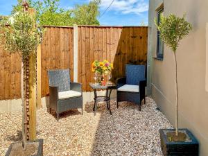 a patio with two chairs and a table with flowers on it at The Old Posthouse Barn - Uk50191 in Weare