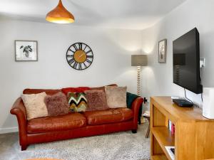 a living room with a brown leather couch and a tv at The Old Posthouse Barn - Uk50191 in Weare