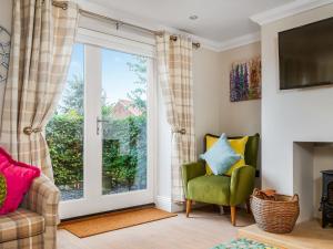 a living room with a window and a green chair at Ridings Cottage in Helmsley