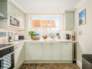 a kitchen with white cabinets and a window at Ridings Cottage in Helmsley