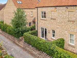 a brick building with bushes next to a street at Ridings Cottage in Helmsley +8 photos