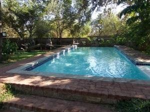 una piscina con un sentiero di mattoni intorno di Nxabii Cottages a Kasane