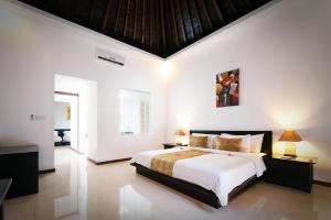 a bedroom with a large bed with white walls at Kebun Villas & Resort in Senggigi