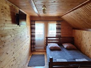 a small room with a bed in a wooden cabin at Садиба Сузір'я in Vorokhta