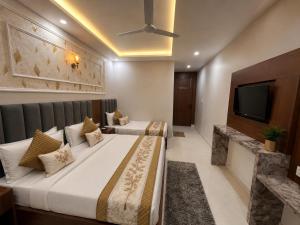a hotel room with two beds and a flat screen tv at Hotel Royal Dot Managed By Sitara Group, Haridwar in Haridwār