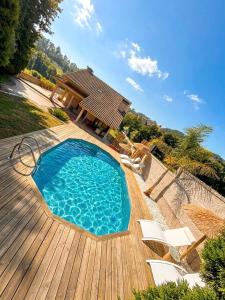 a swimming pool on a wooden deck with chairs and a house at Mazziu's villa in Cans