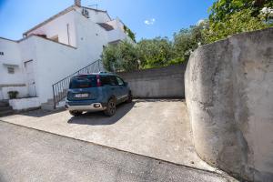 a small car parked in a parking lot next to a wall at Apartments Soni in Postira