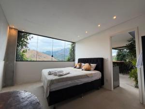 a bedroom with a bed with a large window at Mirante de itaipava in Itaipava