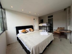 a bedroom with a bed and a table and a chair at Mirante de itaipava in Itaipava