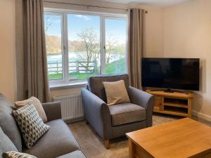 a living room with a couch and chairs and a television at The Narrows in Poolewe